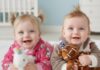 Baby Junge und Baby Mädchen liegen auf dem Bauch und schauen in die Kamera.
